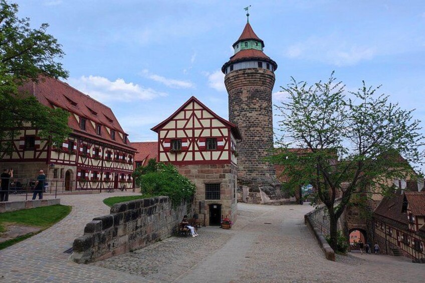 Ett historiskt torg med traditionella hus byggda i korsvirkesstil, ett stentorn och kullerstensgator. 1