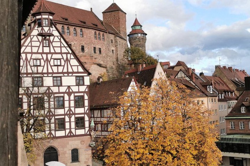 A historic town with timber-framed buildings, a prominent tower, and autumn foliage. 3
