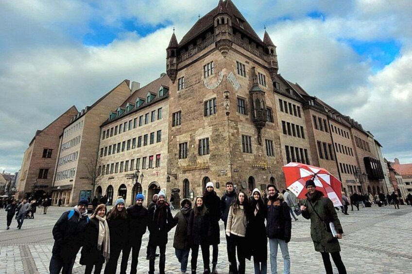 En grupp människor som står framför en historisk byggnad med ett klocktorn. 5