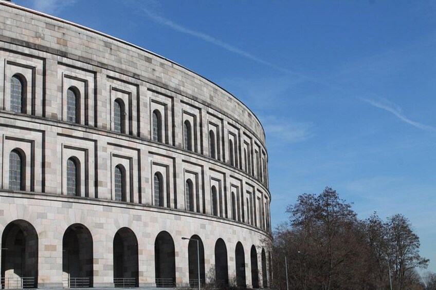 A large, curved building with multiple arched windows and a stone facade. 2