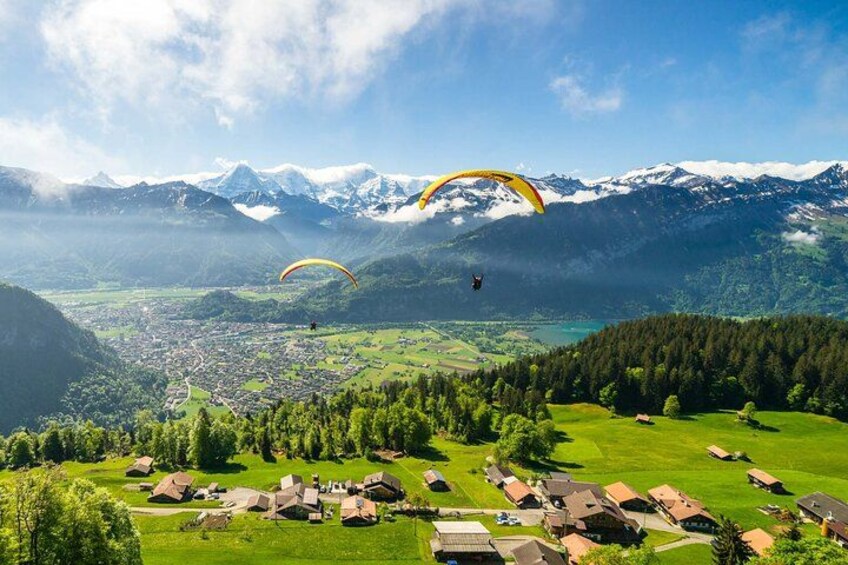 Bergachtig landschap met twee paragliders boven een dorp. 5