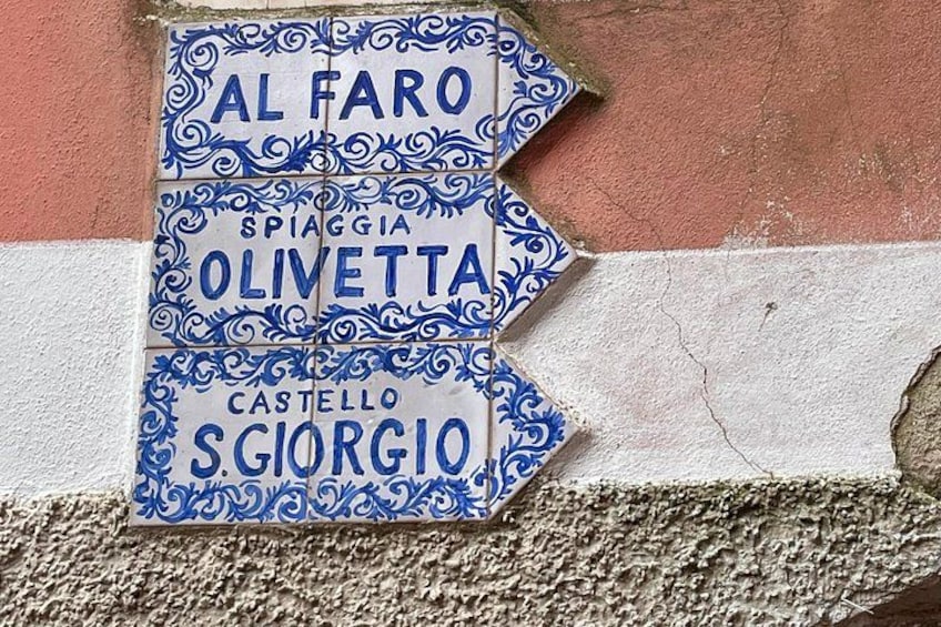 A street sign with names 'Al Faro,' 'Spia Ggia Olivetta,' and 'Castello S Giorgio.' 1