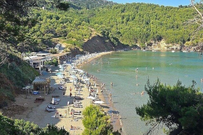 A beach with boats, people, and a forested hillside. 5