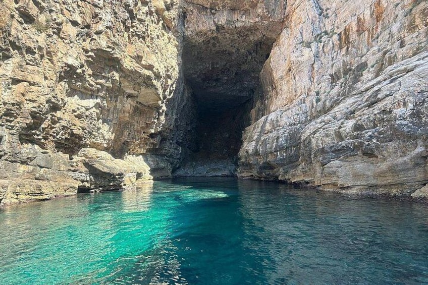 A natural cave entrance with clear turquoise water. 4
