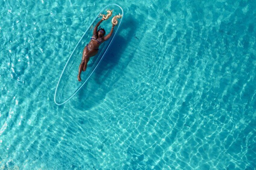En person flyder i en klar, blå pool med en flydering. 5