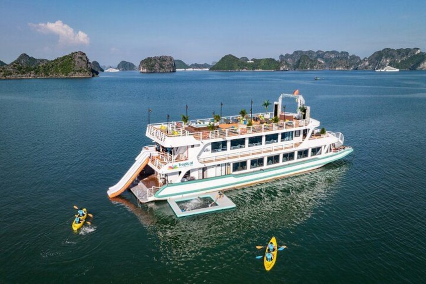 A large cruise ship with a slide, surrounded by calm waters and distant islands. 1