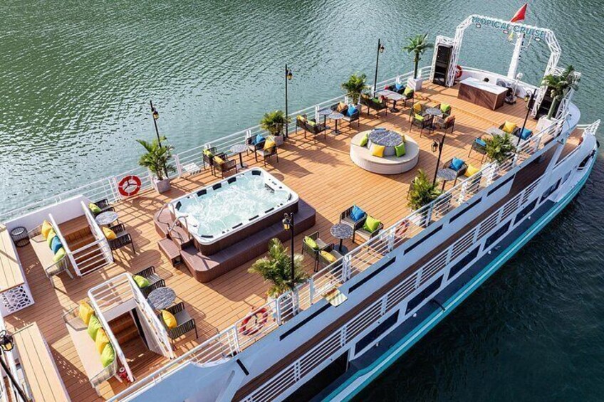 A cruise ship deck with outdoor seating, a hot tub, and a tropical-themed bar area. 3