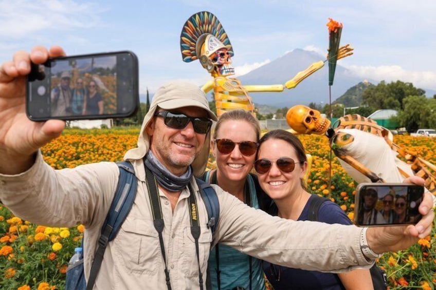A person taking a selfie with a colorful skeleton decoration in the background. 1