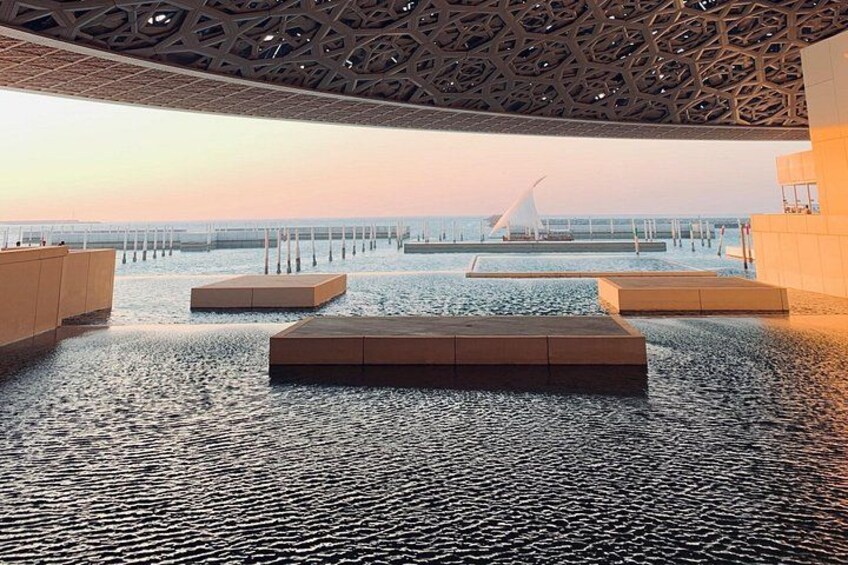 Una fuente de agua interior con asientos geométricos y vistas a un puente. 4