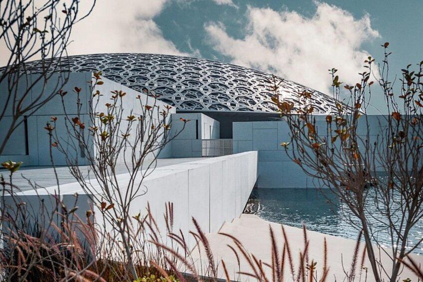 Una estructura arquitectónica moderna con un diseño de techo geométrico, rodeada por una masa de agua y vegetación escasa. 5