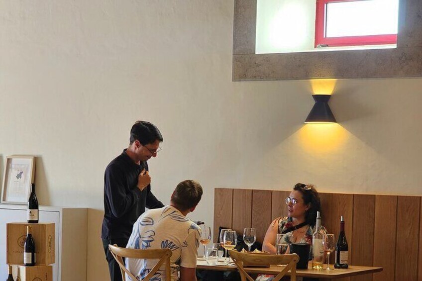 A restaurant interior with wooden paneling, a table with wine glasses, and a person standing by the counter. 3