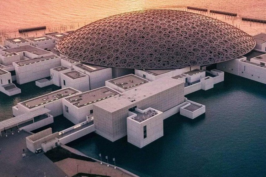 Un edificio grande y circular con techo decorado, rodeado de estructuras más pequeñas y una masa de agua. 3