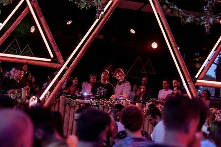 A DJ performing at an outdoor event with geometric lighting structures. 4