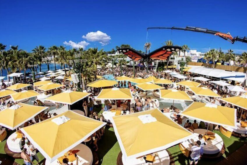 Een druk strand met gele parasols en palmbomen. 2