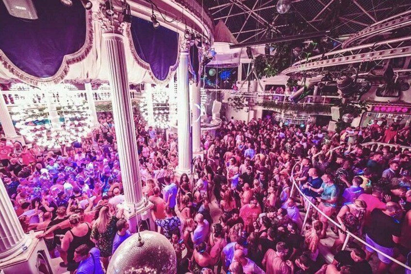 A crowded indoor event with ornate columns and a disco ball. 2