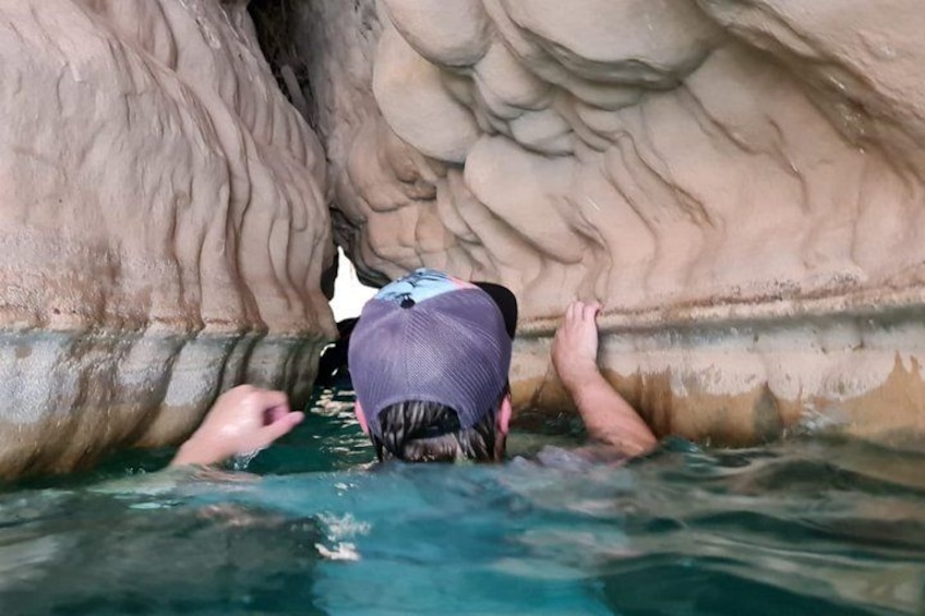 A person swimming in a natural pool with rocky walls. 2