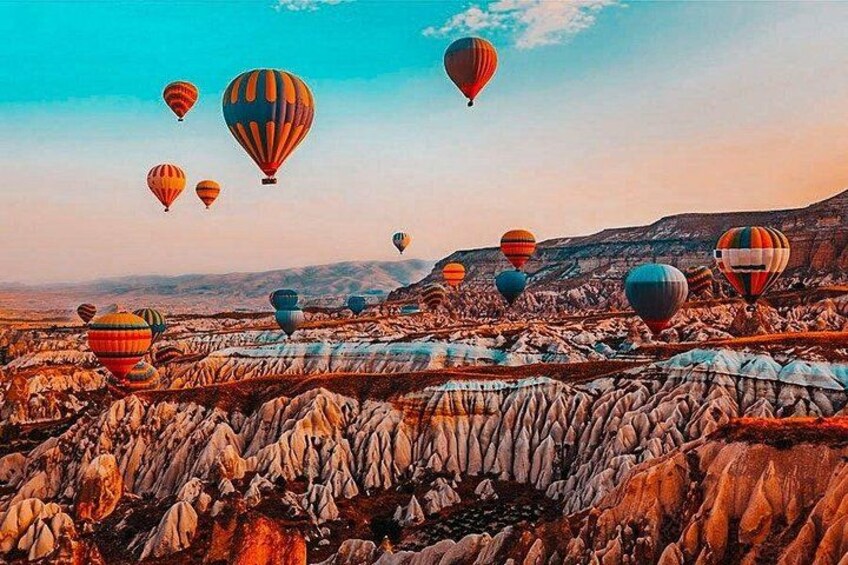 A landscape with multiple hot air balloons and a rugged terrain. 5