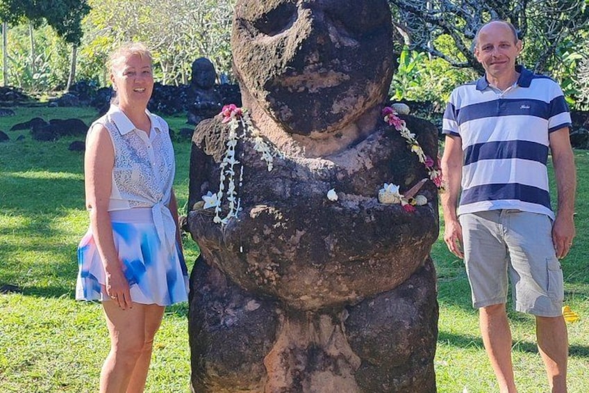 A large stone statue with floral decorations in a grassy area. 3