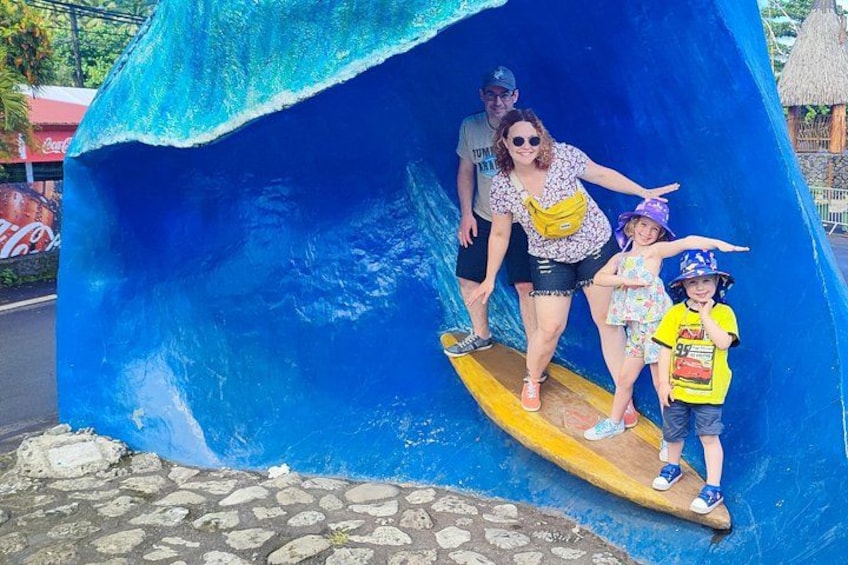 A family on a surfboard in a blue wave-themed structure. 2