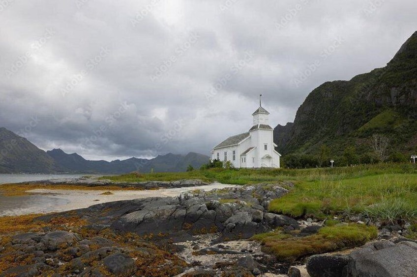 Eine weiße Kirche an einer felsigen Küste, im Hintergrund Berge. 5