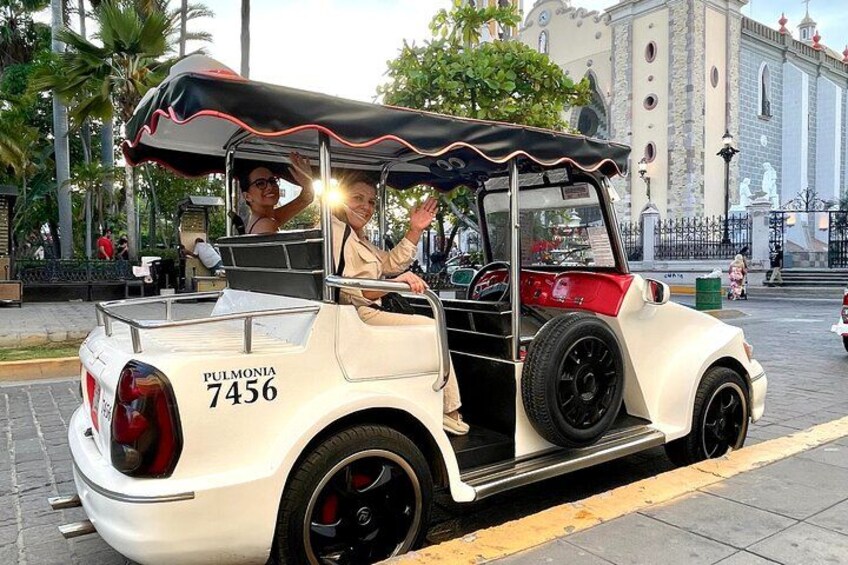 Ein Oldtimer mit schwarzem Dach und roten Akzenten steht an einer Stadtstraße. 5