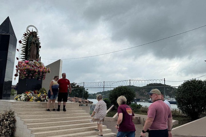 Eine Gruppe von Menschen geht eine Treppe hinauf zu einer Statue mit Blumen. 4