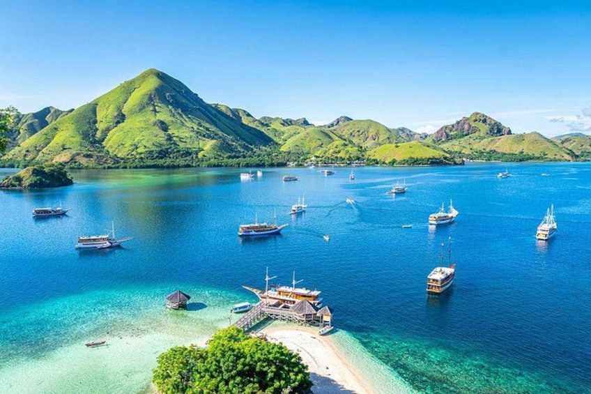 A coastal scene with boats, clear turquoise water, and green hills. 4