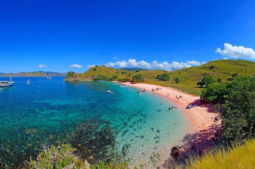 A beach with clear turquoise water, a sandy shore, and green hills in the background. 3
