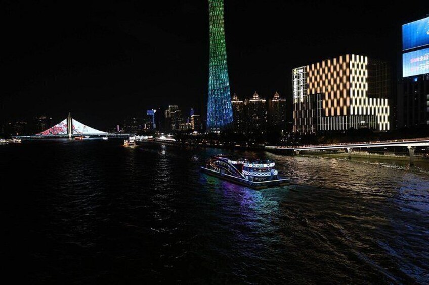 A river with a boat, a bridge, and a tall building with colorful lights. 2