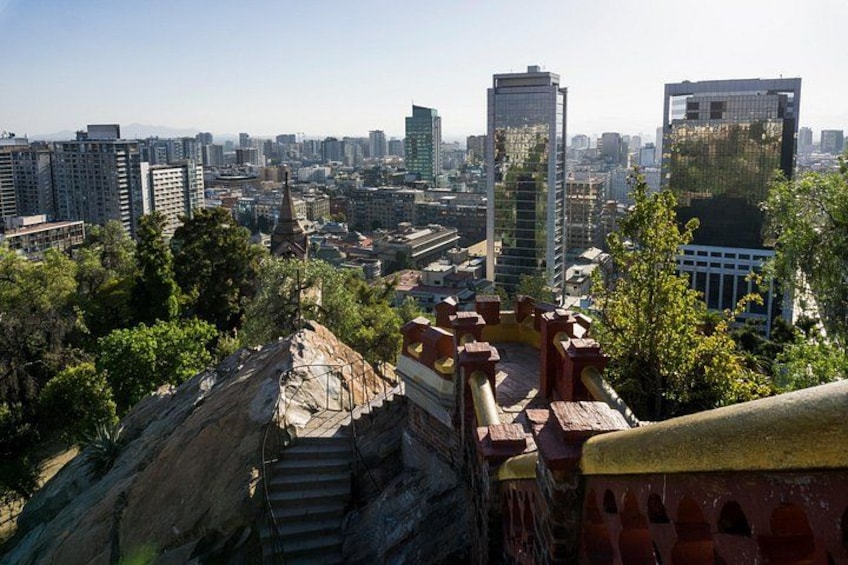 A cityscape with modern high-rise buildings, a historic stone structure, and a clear sky. 1