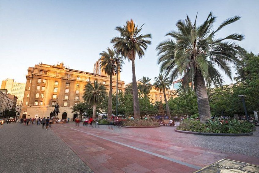 A plaza with palm trees, a statue, and a large building. 2