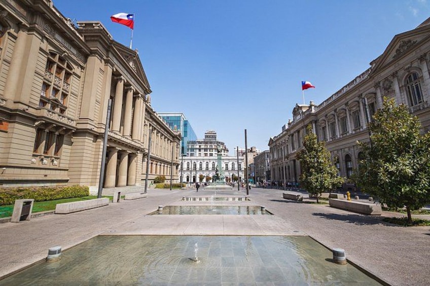 A plaza with a fountain, buildings, and flags. 4
