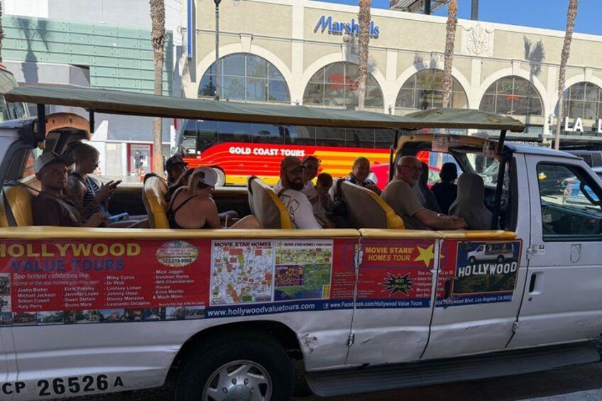 A white tour bus with passengers and a 'Hollywood Value Tours' advertisement. 5
