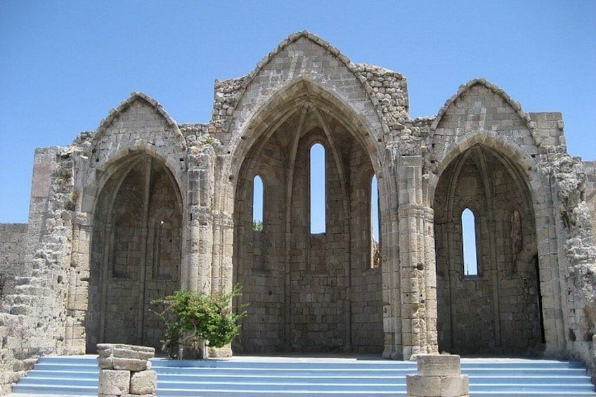 A historic stone building with three large arched doorways and a staircase leading up to it. 5