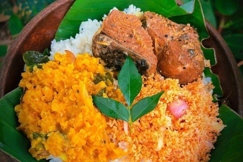 A meal with rice, a yellow curry, and two pieces of meat on a banana leaf. 2