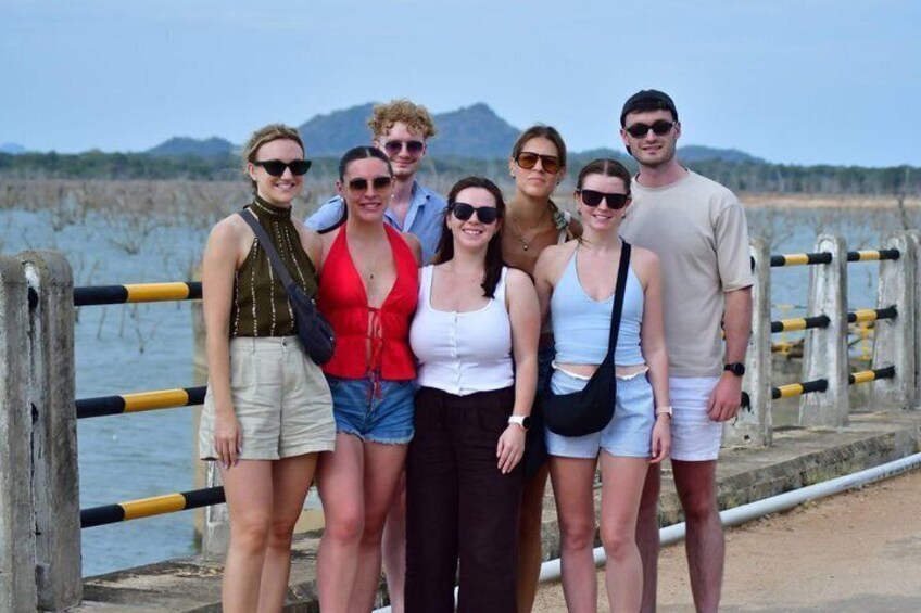 A group of people standing on a concrete pier with a body of water and mountains in the background. 4