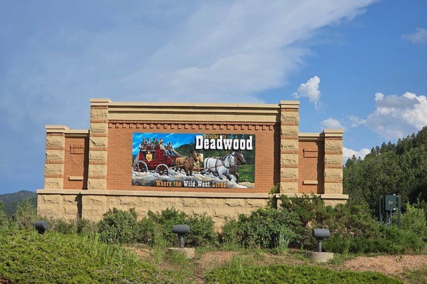 Une grande affiche publicitaire représentant une calèche tirée par des chevaux, avec le mot « Deadwood » inscrit dessus. 4