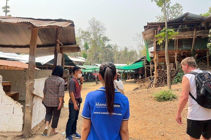 A group of people in a rural setting with makeshift structures and a dirt ground. 5