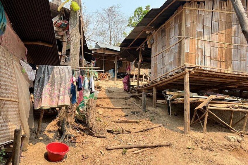 A rural village with wooden houses, a dirt path, and a red bucket. 4
