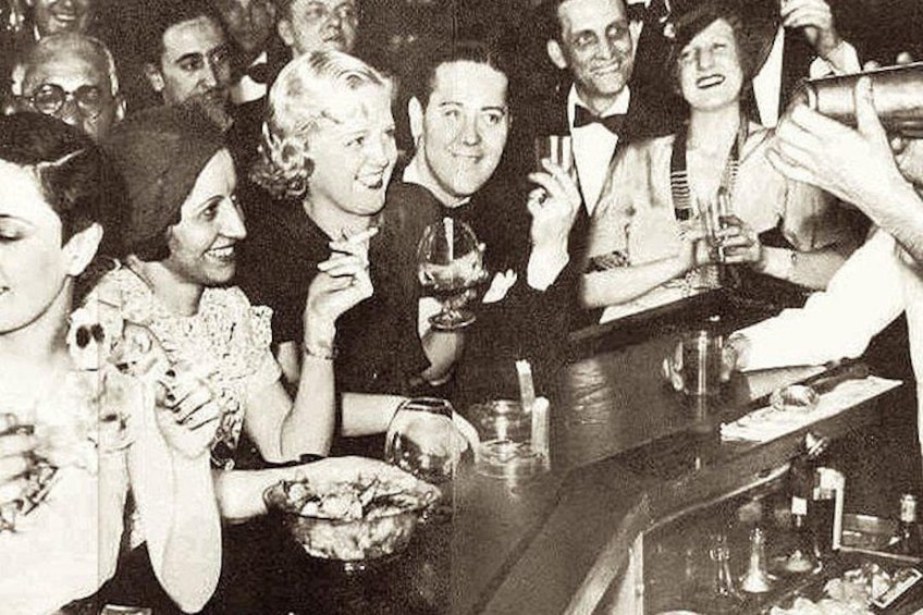 Eine Gruppe von Menschen in einer Bar, einige halten Getränke und stoßen an. 5