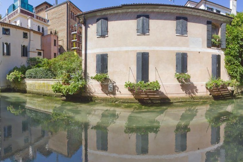 A canal with buildings reflecting on the water, surrounded by greenery. 3