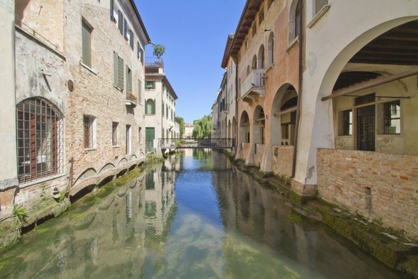 A narrow canal flanked by historic buildings with arched windows and balconies. 4