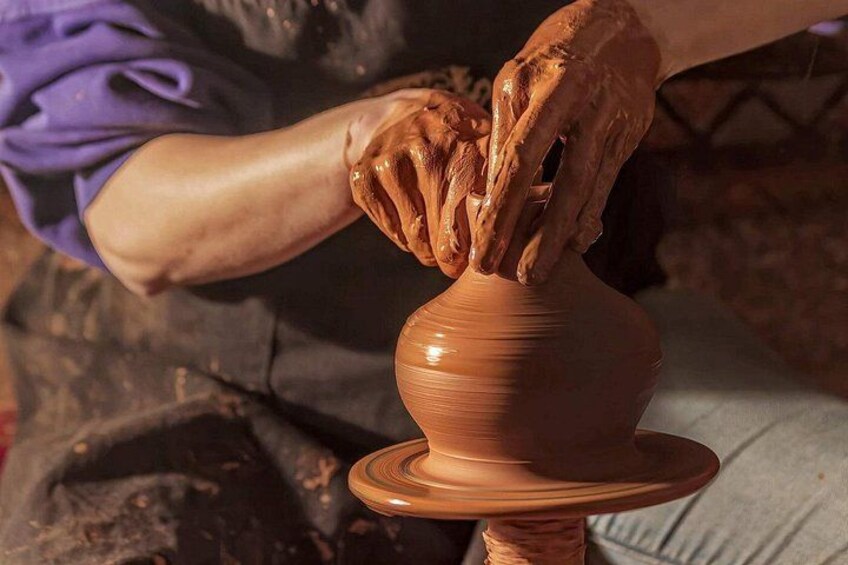 Hands shaping a clay pot on a pottery wheel. 3