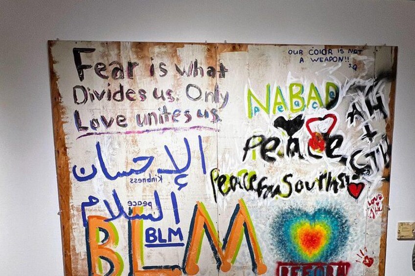 Una pared con grafitis y texto, incluyendo frases como 'El miedo nos divide. Solo el amor nos une' y 'NABAD PEACE'. 4