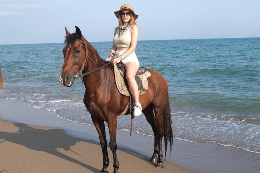 Una persona cavalca un cavallo su una spiaggia, con l'oceano sullo sfondo. 4
