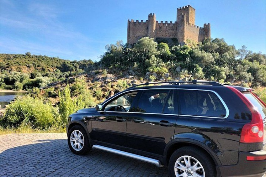 A black SUV parked on a cobblestone path with a castle in the background. 2