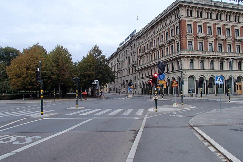 Una intersección urbana con semáforos, cruces peatonales y un gran edificio histórico. 4