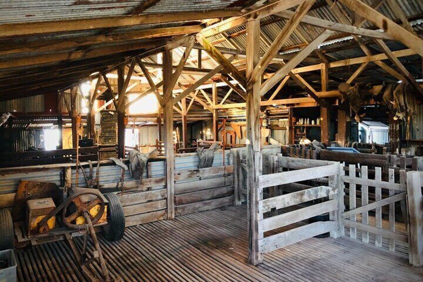 A rustic barn interior with wooden beams, a corrugated metal roof, and a wooden fence. 3