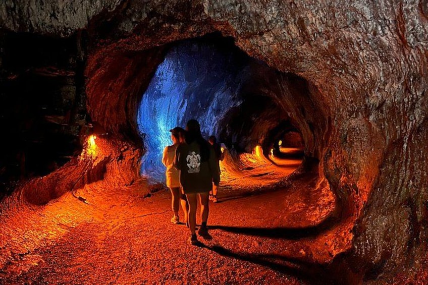 A cave with a blue illuminated opening and people standing inside. 4