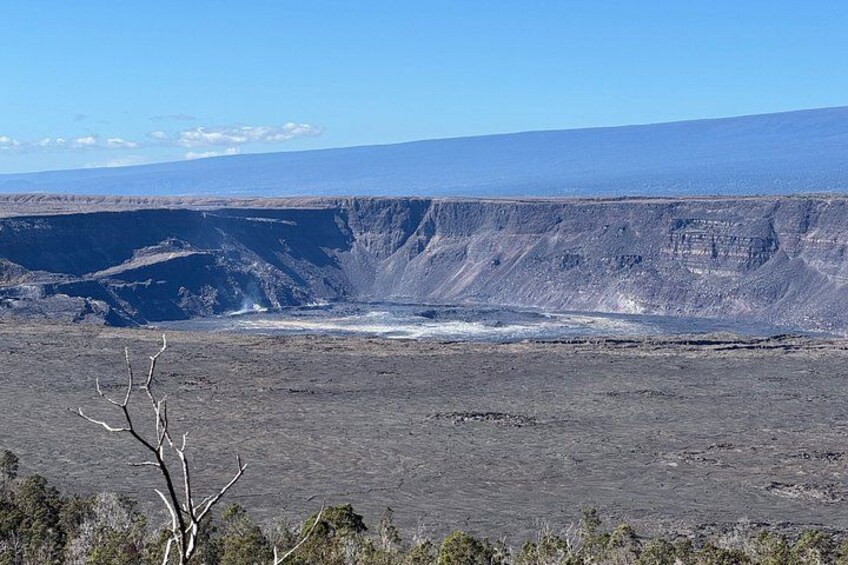 A vast volcanic landscape with a crater, sparse vegetation, and distant mountains. 2